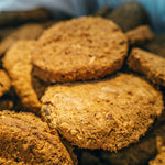 A close-up, top-down view inside a bag of Artisan Raw freeze-dried dog food, showing the fibrous texture and consistent shape of the raw meal pucks.