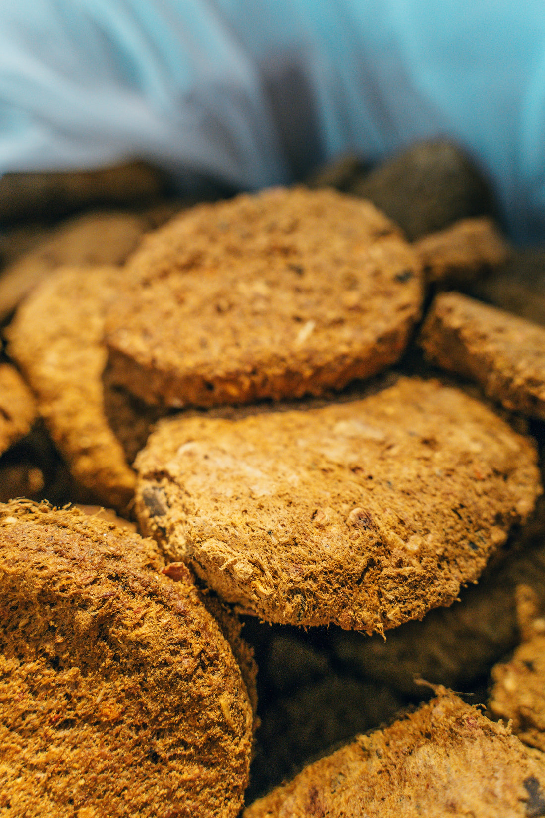 A close-up, top-down view inside a bag of Artisan Raw freeze-dried dog food, showing the fibrous texture and consistent shape of the raw meal pucks.