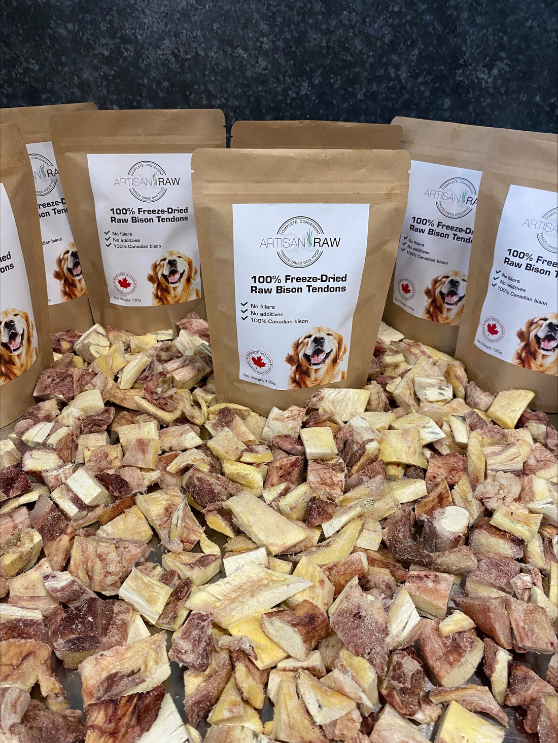 Several Artisan Raw Bison Tendons treat bags arranged upright on a bed of dried bison tendon pieces.